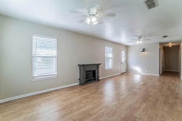a view of a livingroom with a fireplace a ceiling fan and windows