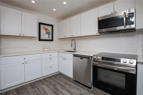a kitchen with cabinets stainless steel appliances and wooden floor