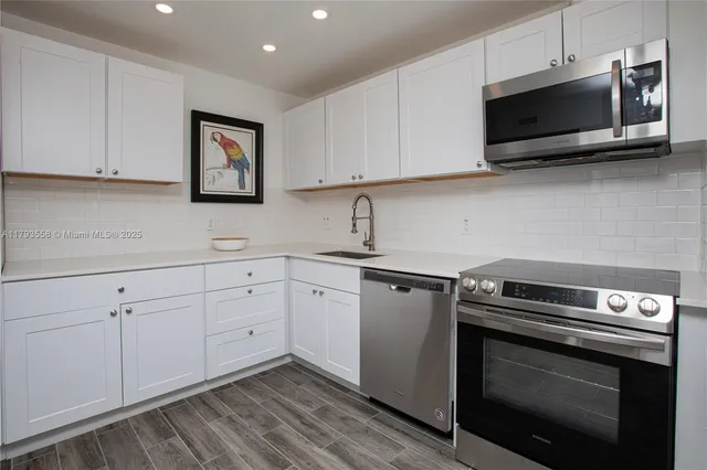 a kitchen with cabinets stainless steel appliances and wooden floor