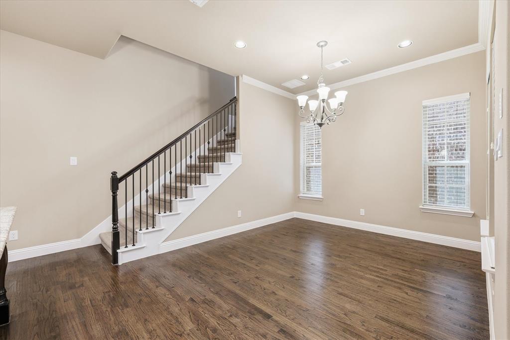 768 Huntingdon Street Coppell, TX 75019 - Photo 18 of 37 Elegant dining area with hardwood floors, crown molding, chandelier lighting, and a staircase with classic iron railing detail.
