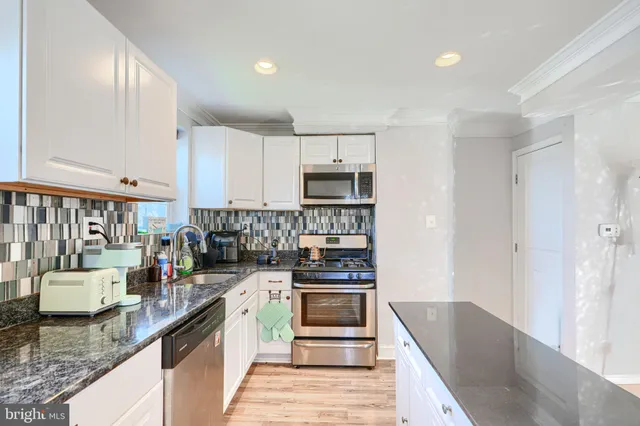 a kitchen with white cabinets and stainless steel appliances