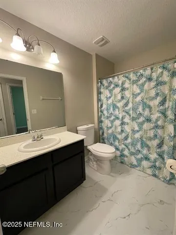 a bathroom with a sink a toilet and shower curtain