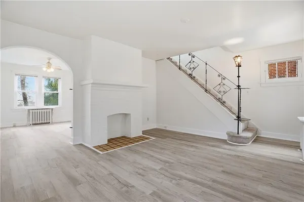 a view of an empty room with wooden floor and stairs