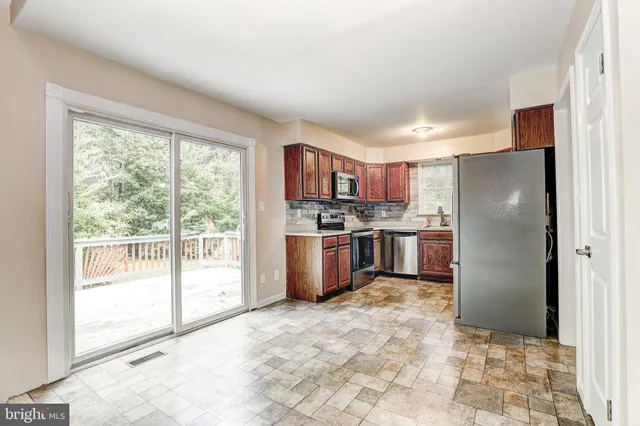 a kitchen with stainless steel appliances a refrigerator a stove a sink and a large window