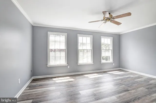a view of empty room with wooden floor and fan