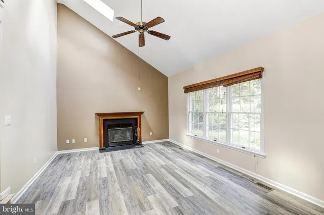 an empty room with windows fireplace and wooden floor