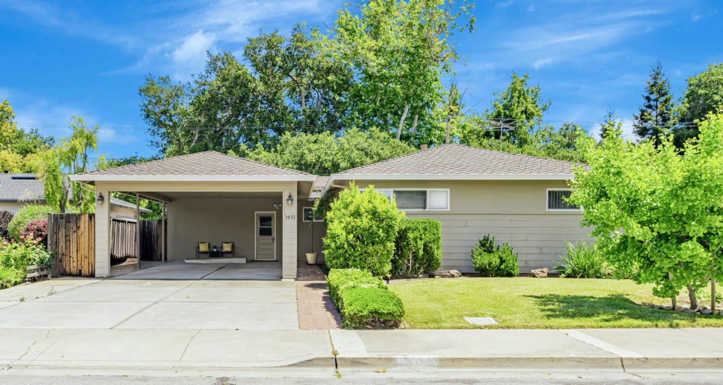 a view of a house with a yard plants and large tree