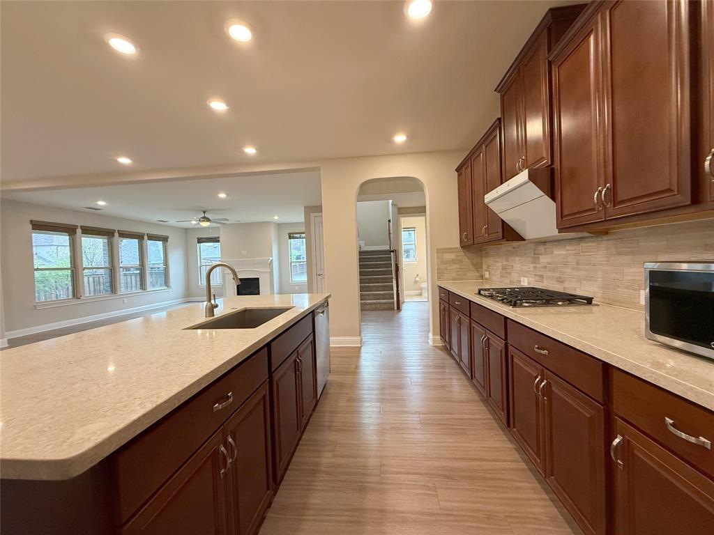 9829 Sharps Road Frisco, TX 75035 - Photo 39 of 40 Kitchen featuring light stone countertops, a fireplace, arched walkways, open floor plan, and recessed lighting