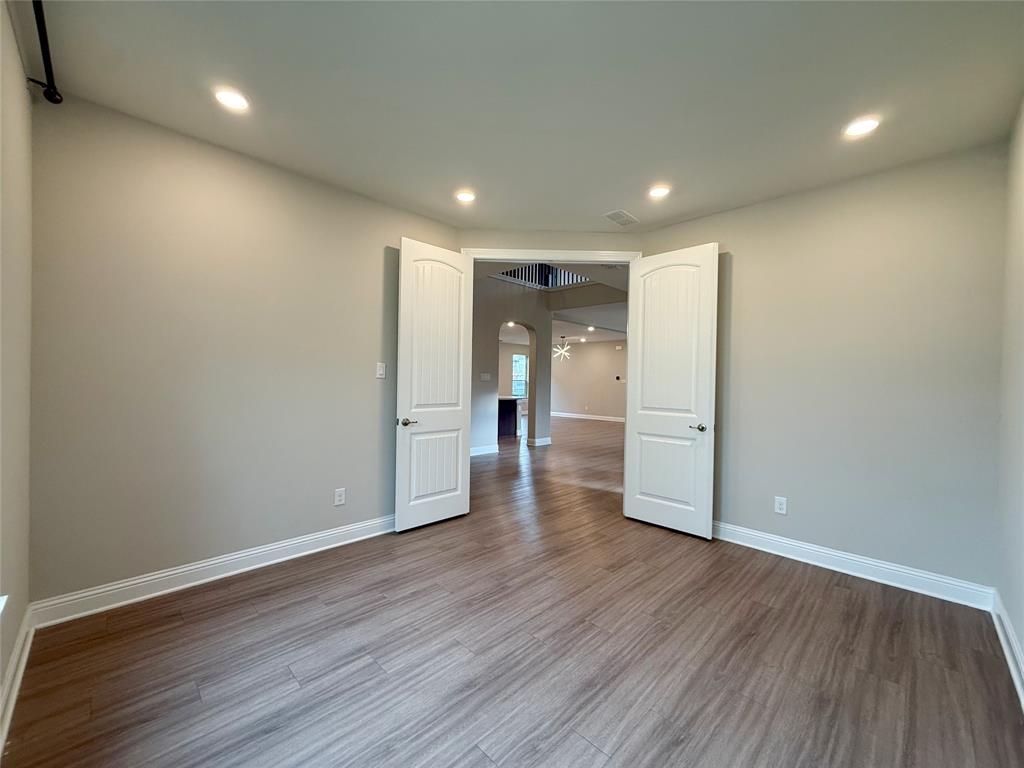 9829 Sharps Road Frisco, TX 75035 - Photo 4 of 40 Unfurnished room with arched walkways, recessed lighting, and dark wood-style flooring