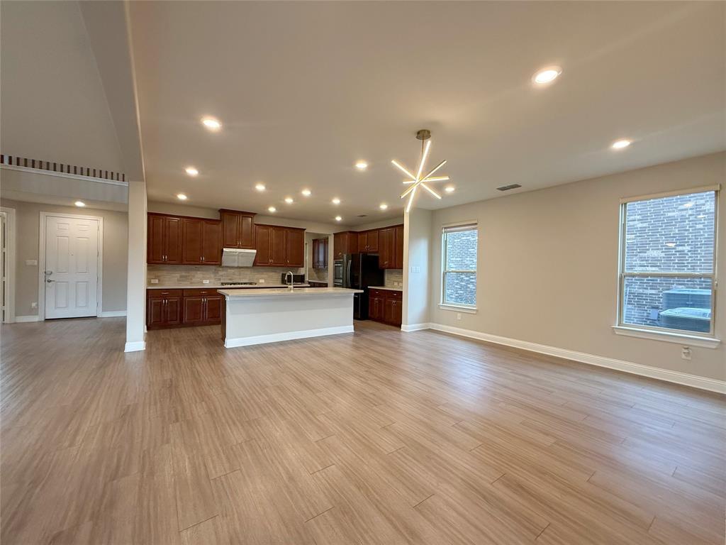 9829 Sharps Road Frisco, TX 75035 - Photo 38 of 40 Kitchen with open floor plan, a kitchen island with sink, white microwave, light wood-type flooring, and recessed lighting