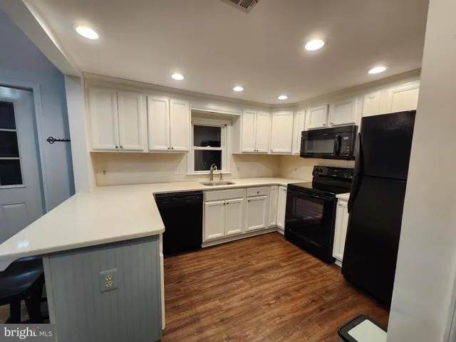 a kitchen with a refrigerator a sink and dishwasher with wooden floor