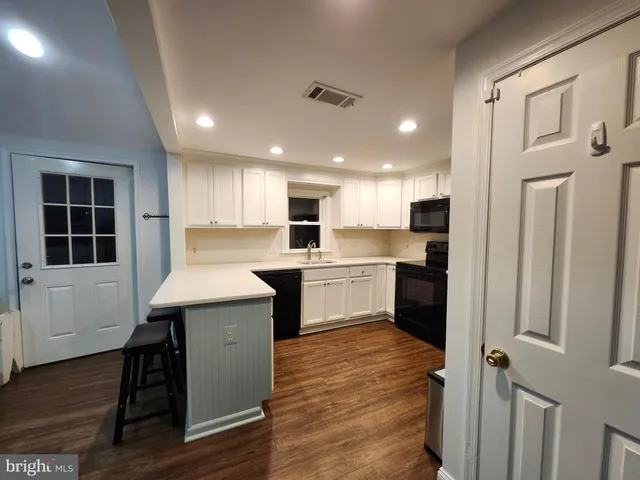 a kitchen with a sink stainless steel appliances wooden floor and cabinets