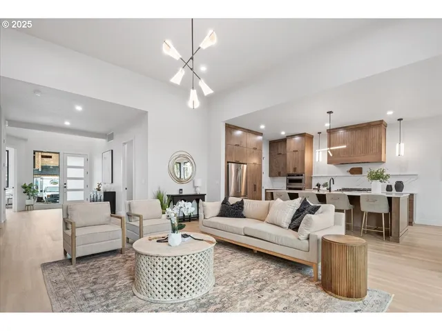 a living room with furniture kitchen view and a chandelier