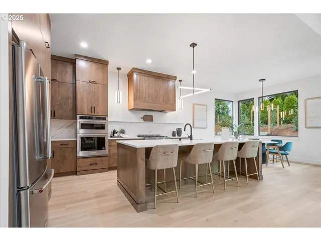 a kitchen with stainless steel appliances kitchen island granite countertop a table chairs and a refrigerator