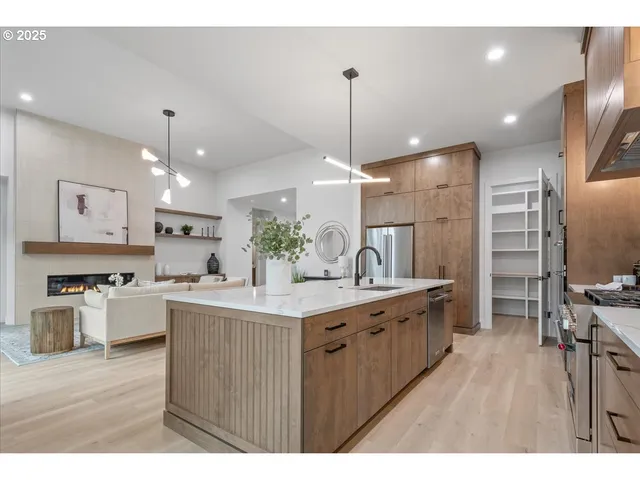 a kitchen with stainless steel appliances kitchen island granite countertop a sink a refrigerator and a wooden cabinets