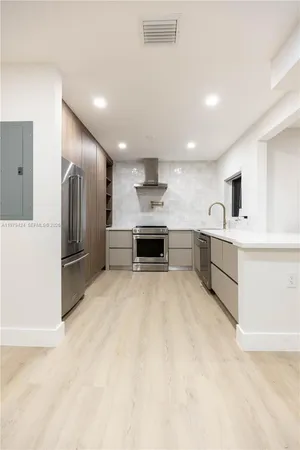a large white kitchen with a sink stainless steel appliances and cabinets