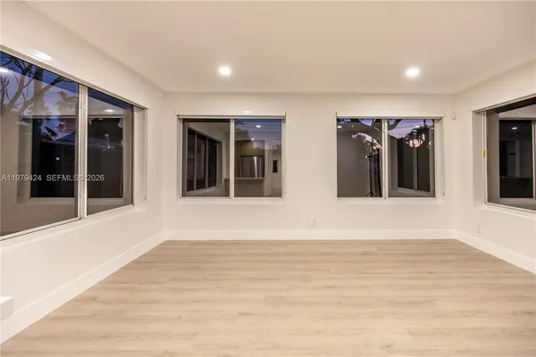 a view of an empty room with wooden floor and windows