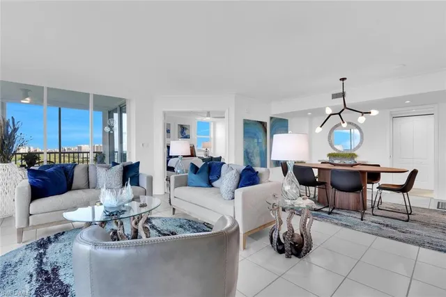 a living room with couches a dining table and a chandelier