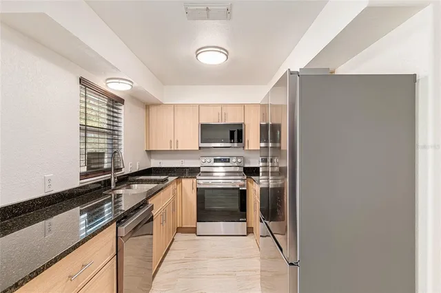 a kitchen with stainless steel appliances granite countertop a stove a sink and a refrigerator