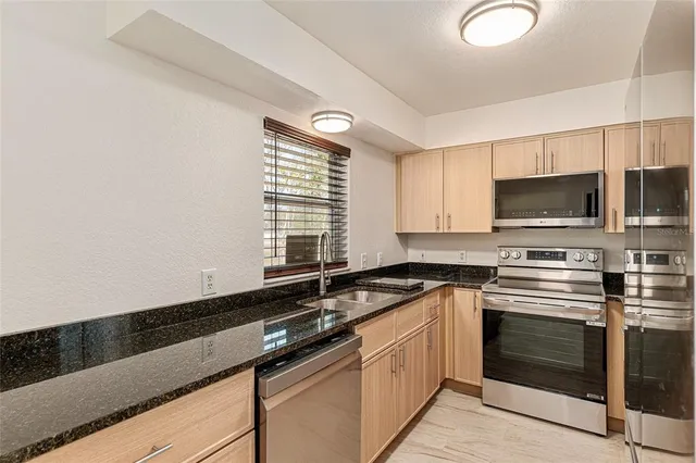 a kitchen with granite countertop a sink cabinets and stainless steel appliances