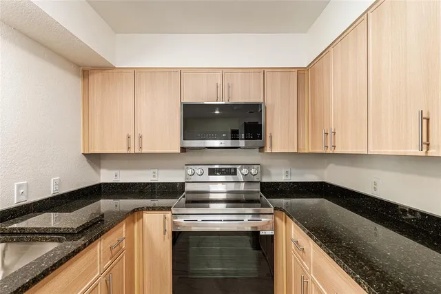 a kitchen with granite countertop a stove sink and cabinets