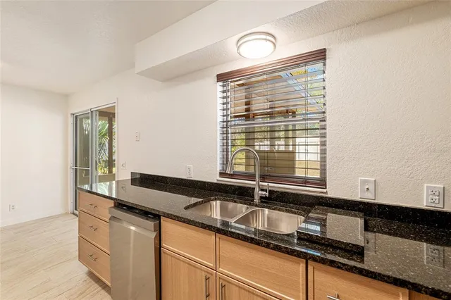 a kitchen with granite countertop a sink and a white wooden cabinets