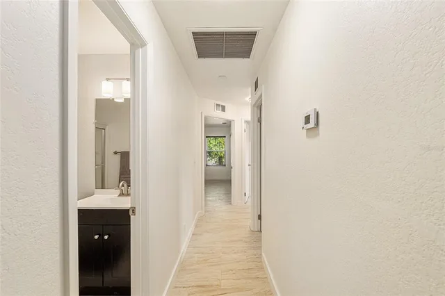 a view of a hallway with wooden floor and a bathroom