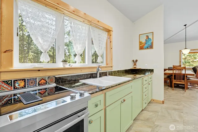 a view of a kitchen counter top space with stainless steel appliances granite countertop a sink and a large window