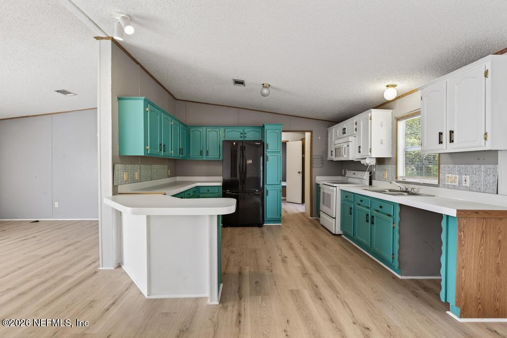 54059 Charles Street Callahan, FL 32011 - Photo 14 of 50 a kitchen with stainless steel appliances a white stove top oven cabinets and a wooden floor