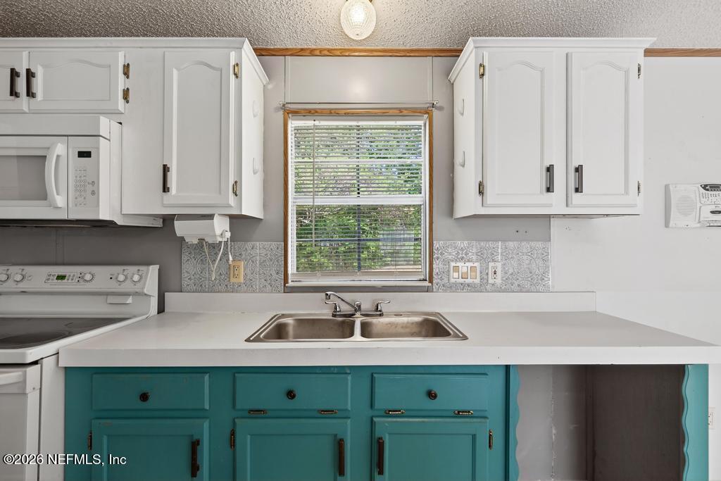 54059 Charles Street Callahan, FL 32011 - Photo 17 of 50 a kitchen with stainless steel appliances granite countertop a sink and a white cabinets