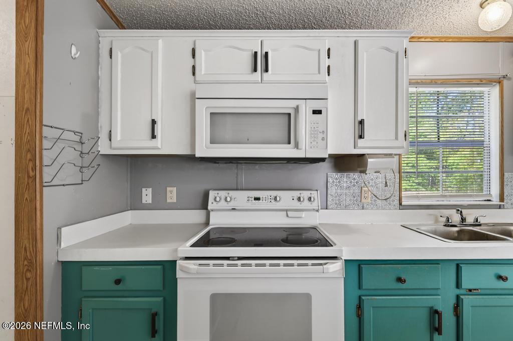 54059 Charles Street Callahan, FL 32011 - Photo 18 of 50 a kitchen with granite countertop white cabinets and white appliances