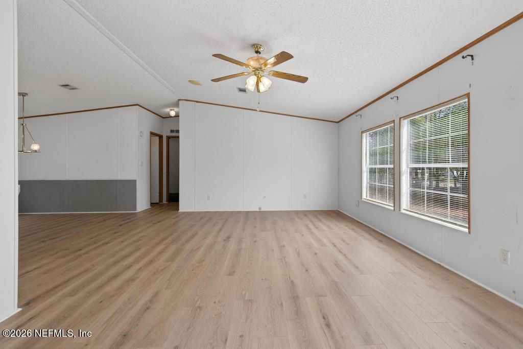 54059 Charles Street Callahan, FL 32011 - Photo 6 of 50 an empty room with wooden floor chandelier fan and windows