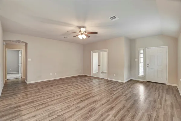 an empty room with wooden floor cabinet and windows