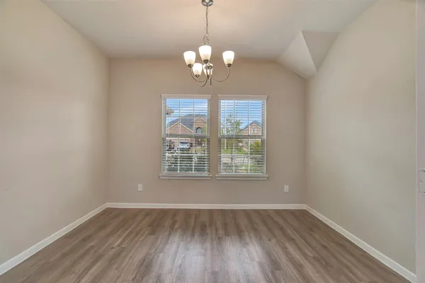 a kitchen with stainless steel appliances granite countertop a refrigerator a sink dishwasher a stove and a dining table with wooden floor