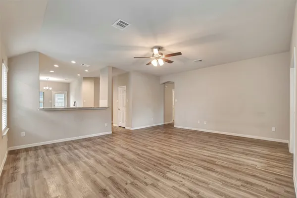 a view of an empty room with a window and wooden floor