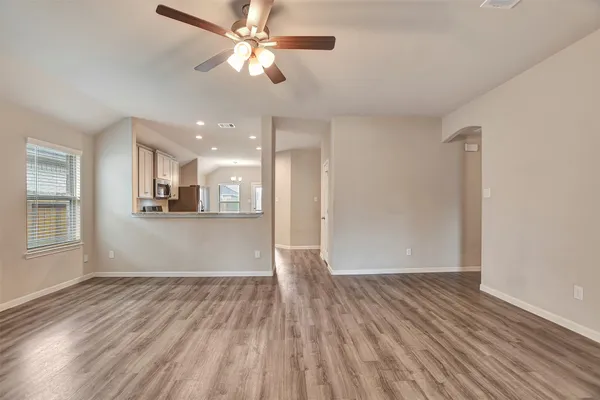 a view of an empty room with wooden floor and a window