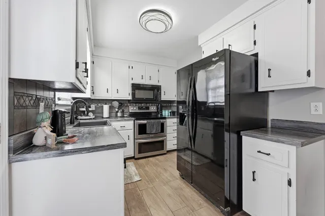 a kitchen with granite countertop a refrigerator stove and sink