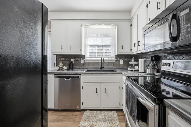 a kitchen with stainless steel appliances granite countertop a sink a stove a microwave and cabinets