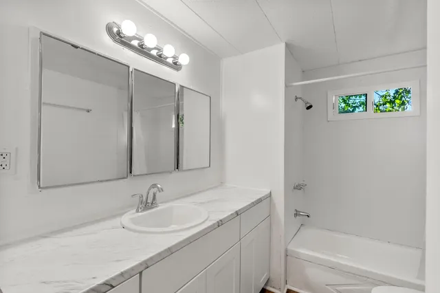 a bathroom with a tub sink and mirror