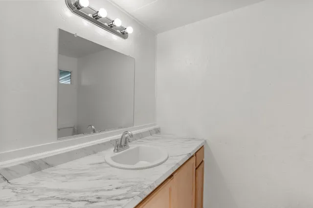 a bathroom with a granite countertop sink and a mirror
