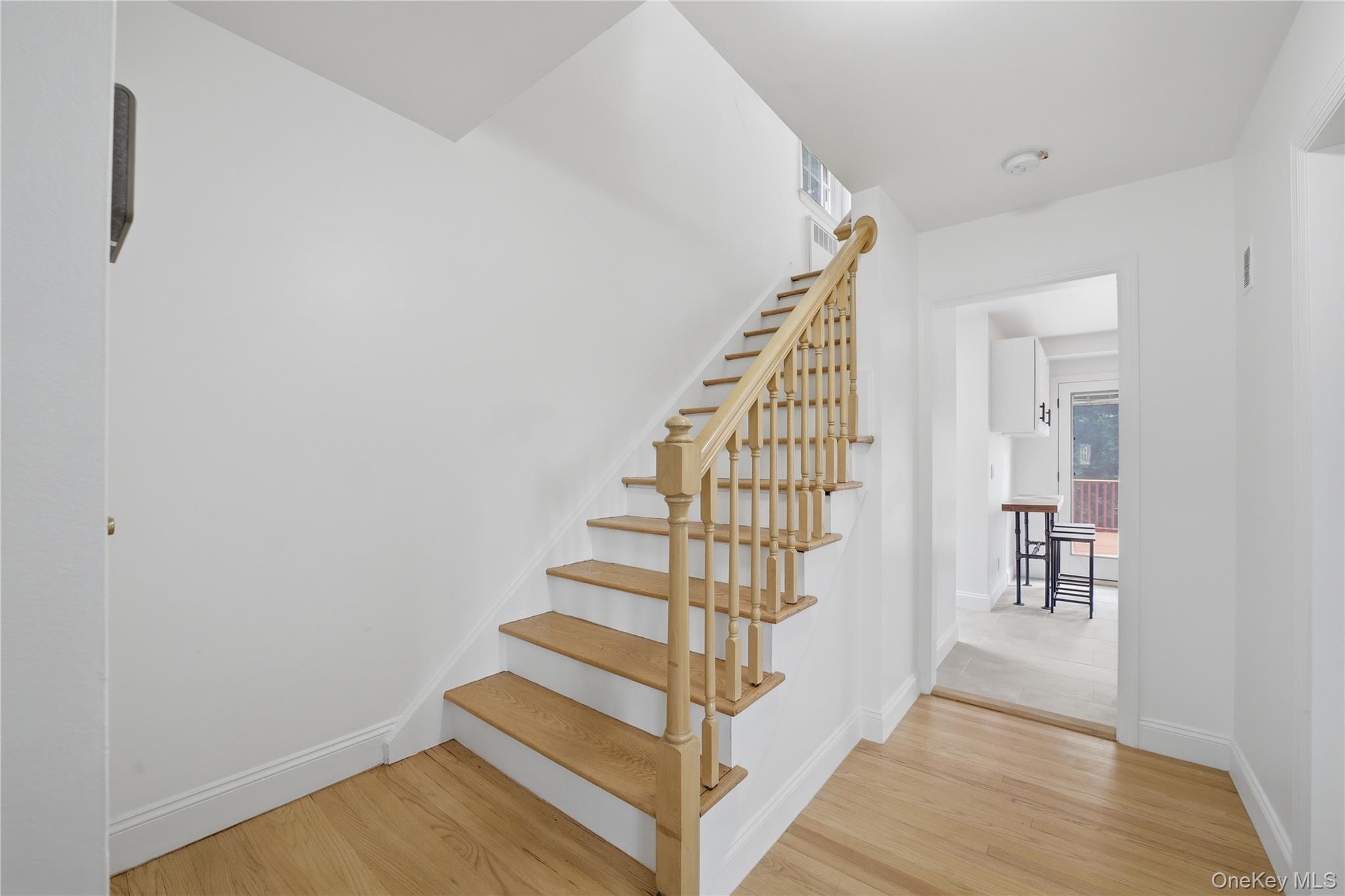 144 Bell Road Scarsdale, NY 10583 - Photo 19 of 49 Hardwood flooring extends from the entryway throughout the lower level, complementing the natural wood staircase with white risers and railing