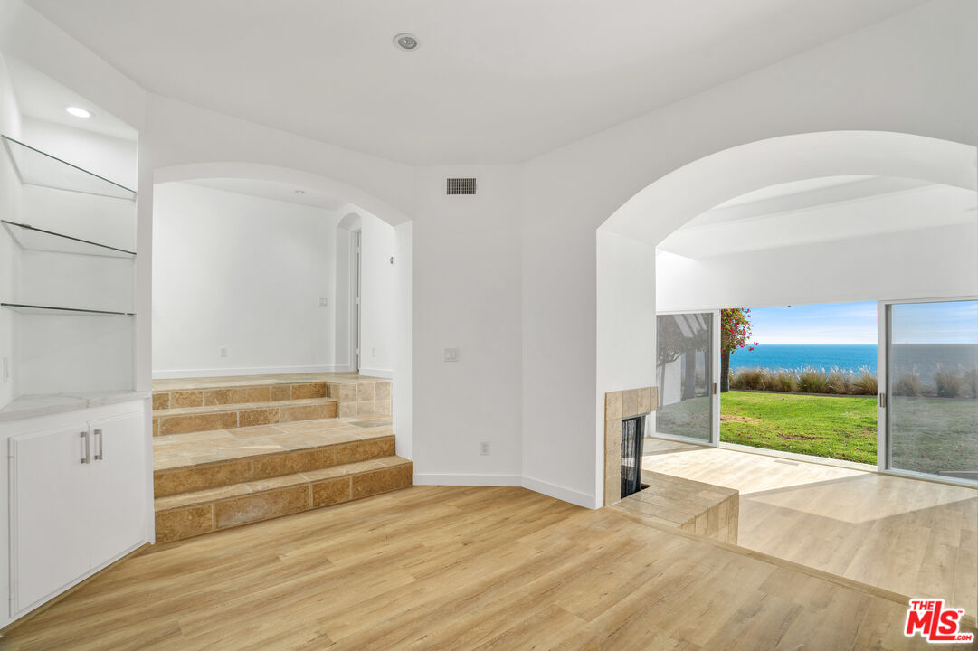 31246 Bailard Road Malibu, CA 90265 - Photo 4 of 31 a view of an empty room with wooden floor and a fireplace