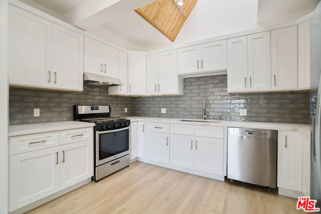31246 Bailard Road Malibu, CA 90265 - Photo 8 of 31 a kitchen with granite countertop white cabinets and white appliances