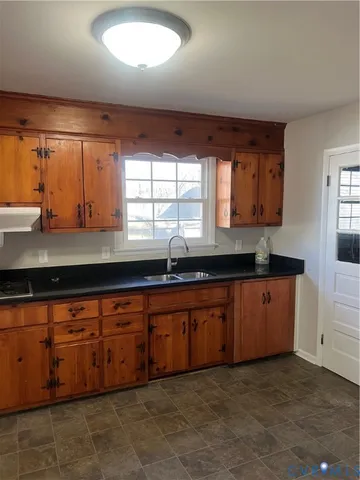 a large kitchen with granite countertop a sink window and cabinets