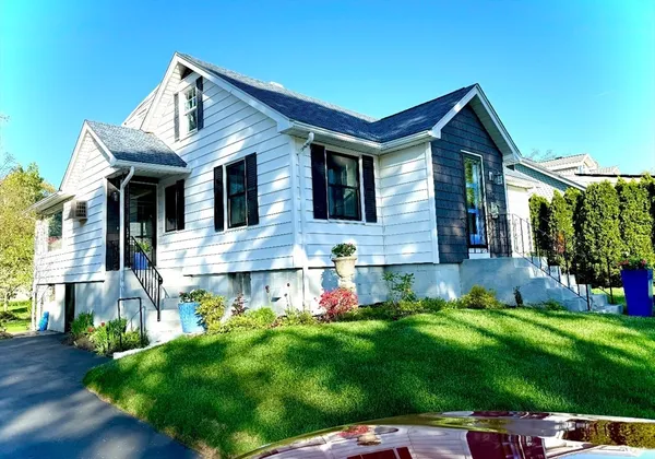 a view of a white house with a big yard and potted plants
