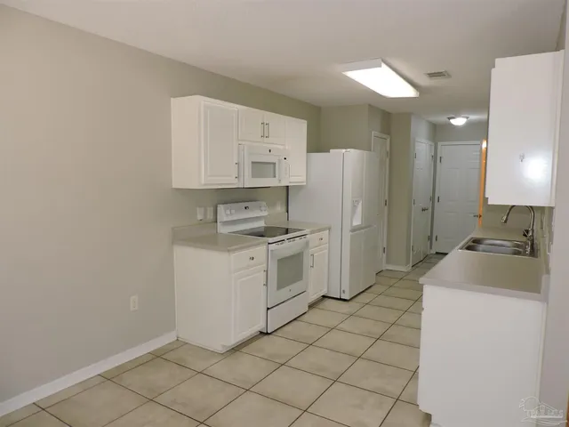 a kitchen with white cabinets and white appliances