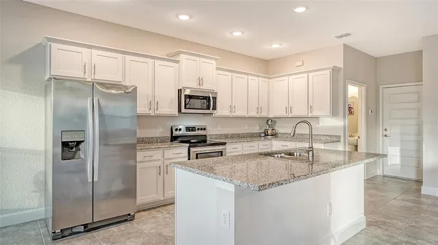 a kitchen with stainless steel appliances granite countertop a refrigerator a sink a stove a microwave and island