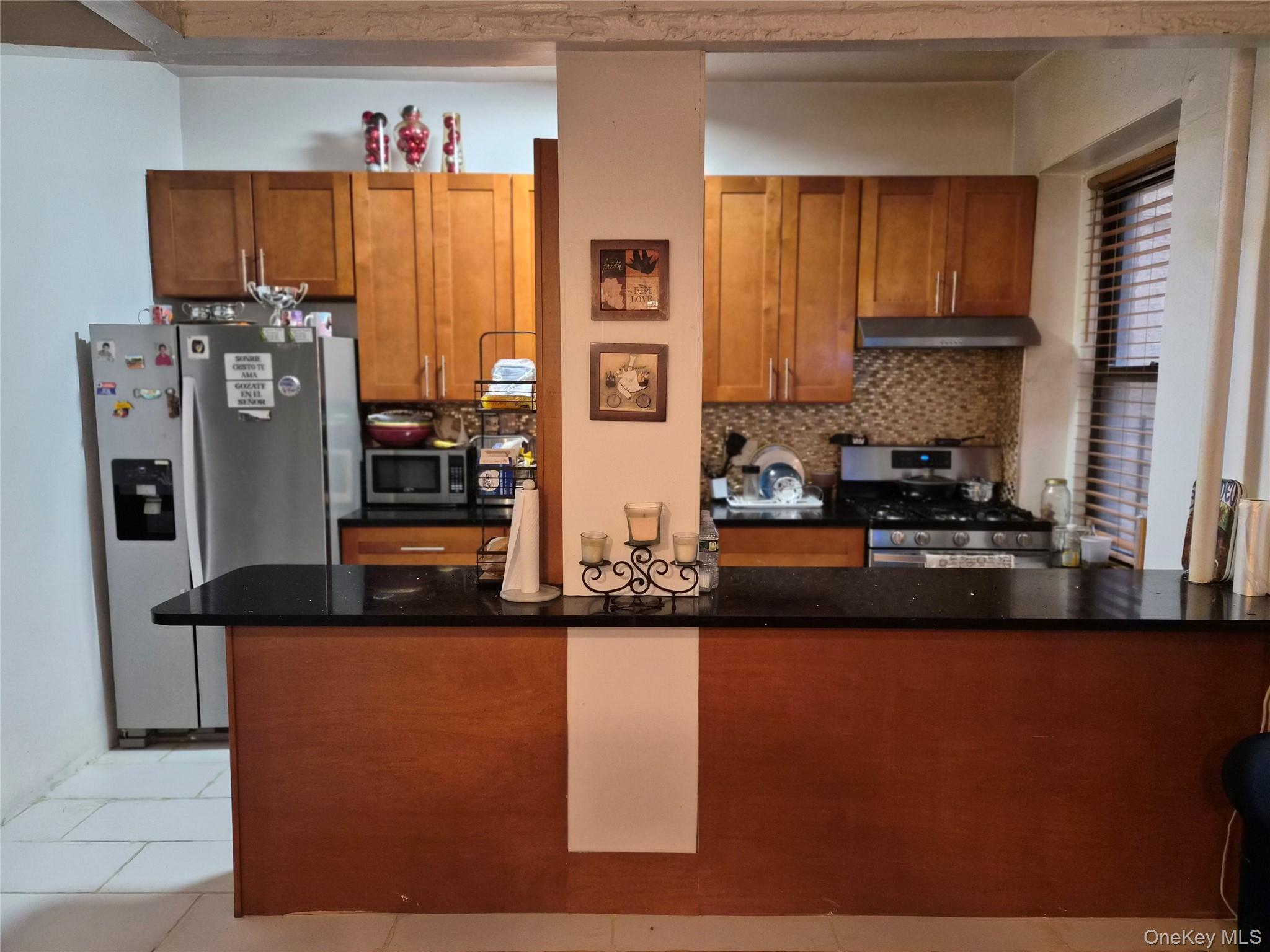 37-21 80th Street, Unit 1R Queens, NY 11372 - Photo 2 of 5 a kitchen with stainless steel appliances granite countertop a refrigerator a stove and a microwave with wooden floor