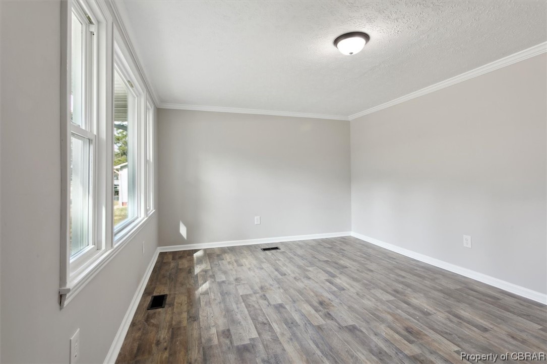 5684 Centerville Road Williamsburg, VA 23188 - Photo 9 of 33 Spare room with dark hardwood / wood-style floors, a textured ceiling, and crown molding