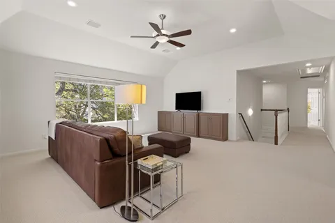 a living room with furniture ceiling fan and a large window